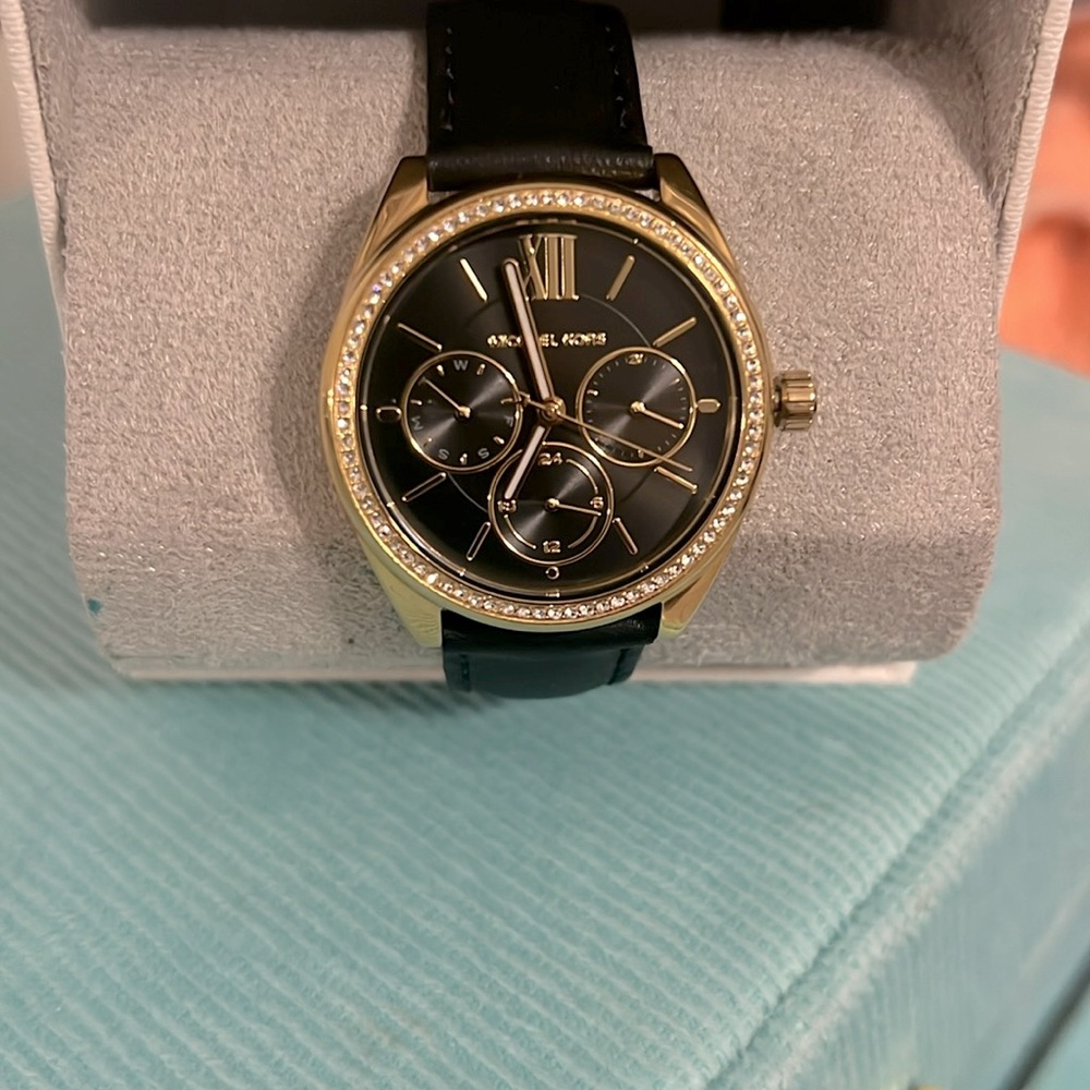 Michael Kors watch, with black leather strap and gold face with rhinestones.